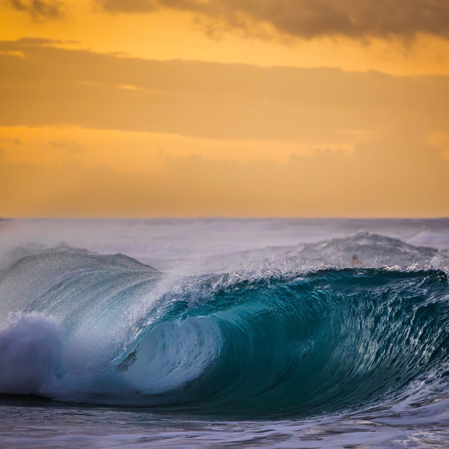 Ocean wave under a golden sunset sky.