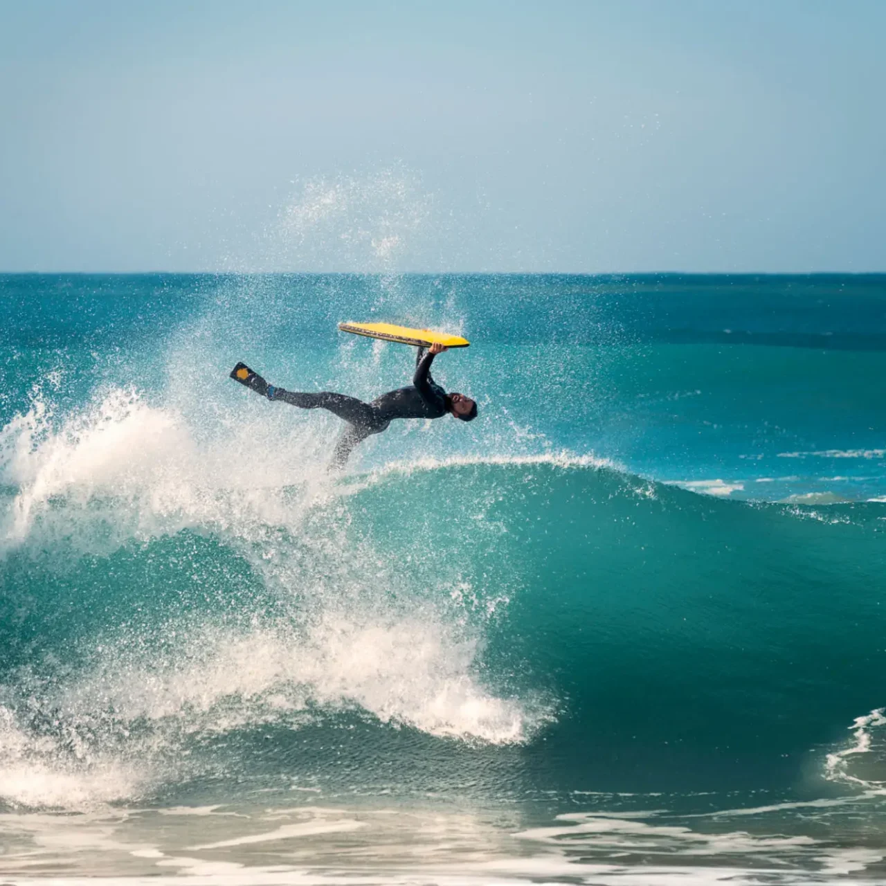 Surfer performing flip on crashing wave.
