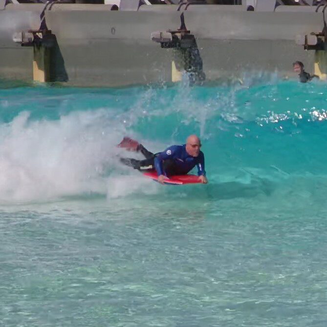 Bodyboarder riding turquoise wave in pool